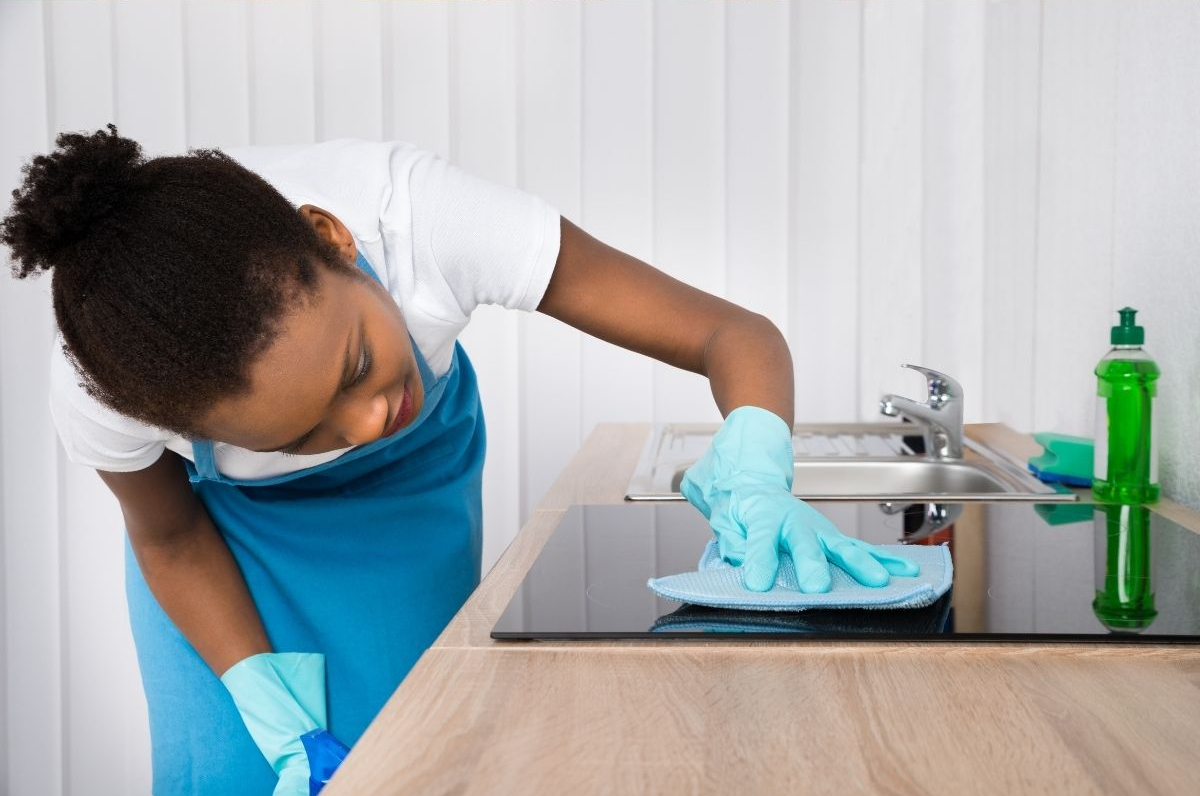 A woman cleaning the induction cooktop next to her kitchen sink
