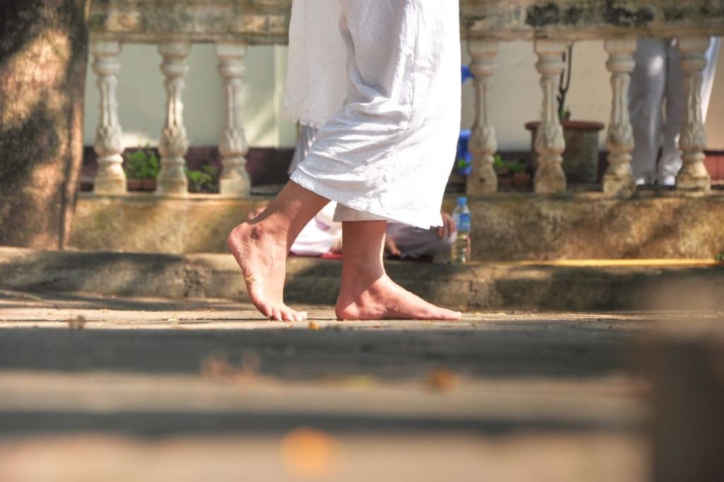 A barefoot person taking a step is shown from the thighs down